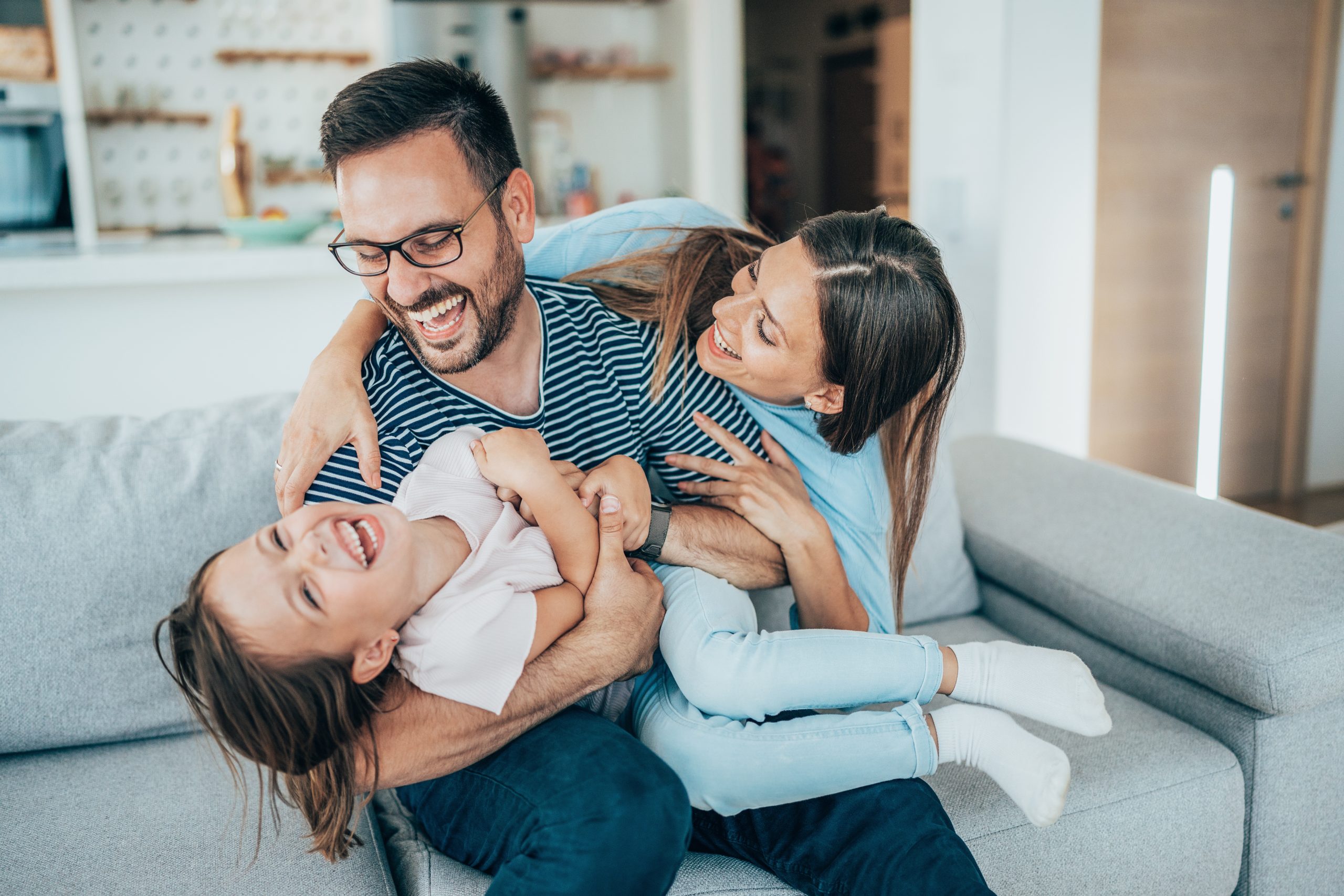Happy family laughing together on a cozy living room sofa