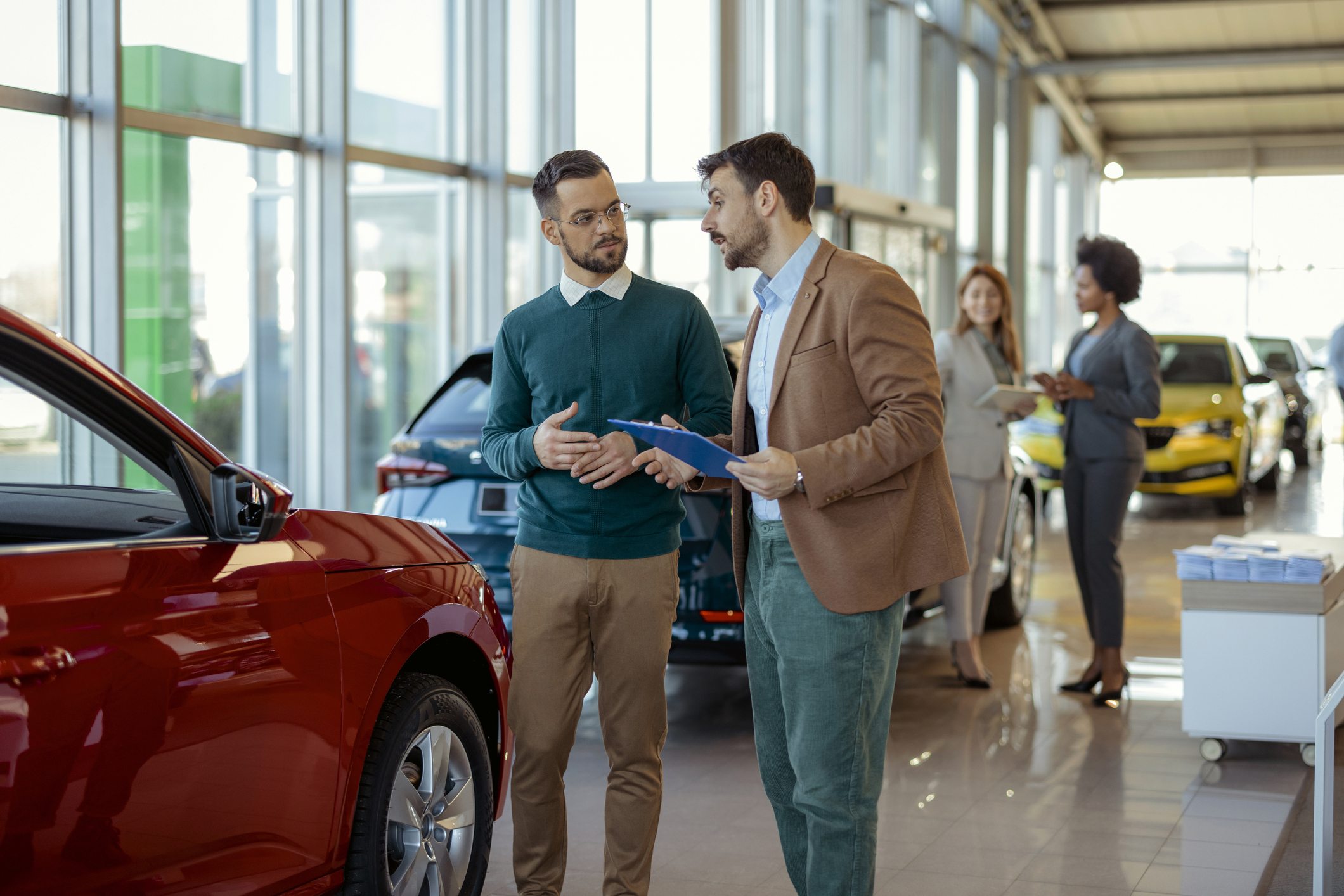 Men discussing in a car showroom with colorful vehicles displayed