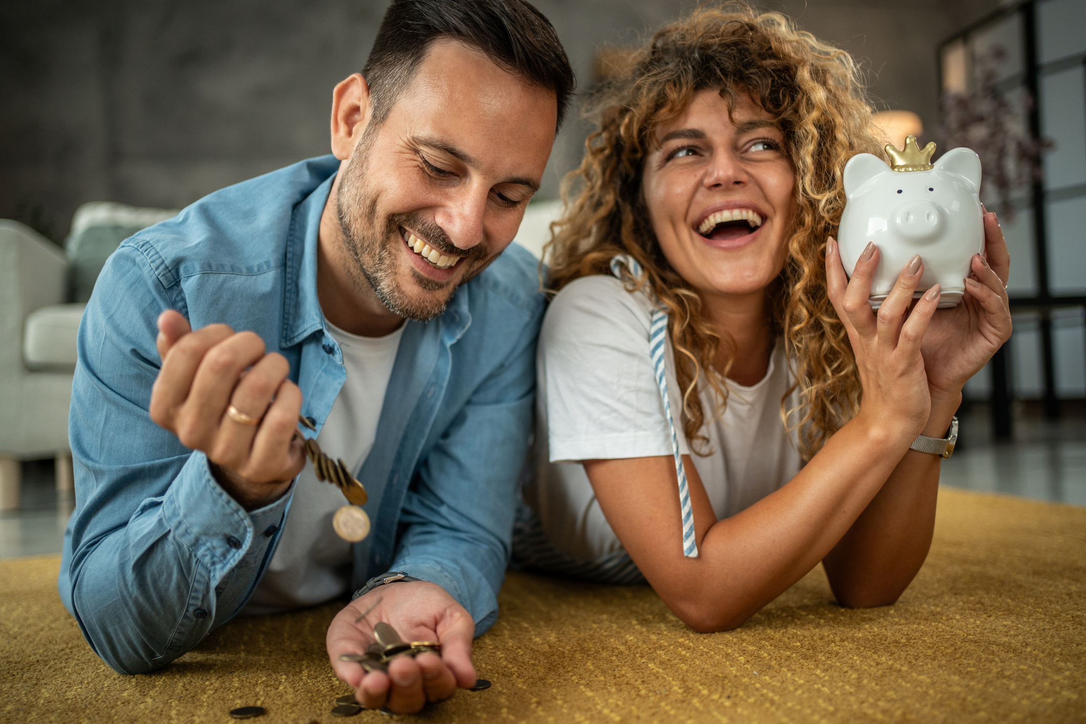 Couple joyfully saving money with coins and piggy bank