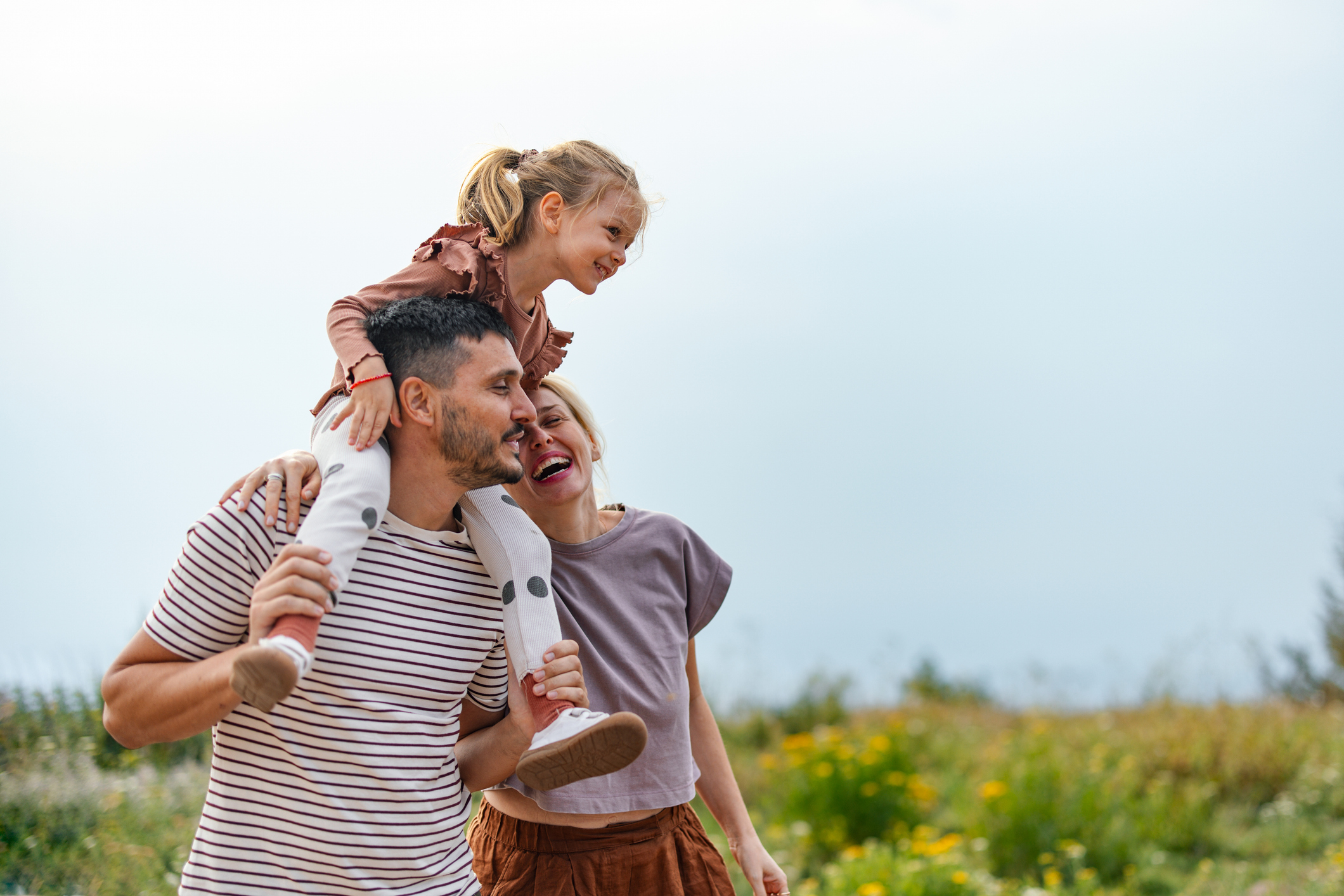 Family enjoying nature with child on shoulders in field
